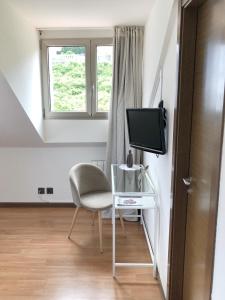 a living room with a chair and a television at Hotel As Hortensias in Corcubión