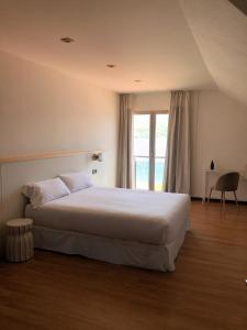 a bedroom with a large white bed and a window at Hotel As Hortensias in Corcubión