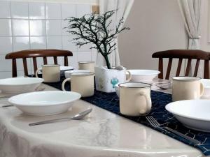 a table with white bowls and utensils on it at Homey 9pax 3BR MRT Cheras Tmn Suntex I HomeBrickz in Cheras