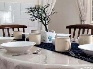 a table with white bowls and utensils on it at Homey 9pax 3BR MRT Cheras Tmn Suntex I HomeBrickz in Cheras