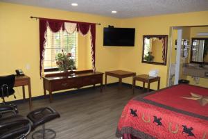 a bedroom with a bed and a desk and a television at Chaparral Motel Hallettsville in Hallettsville