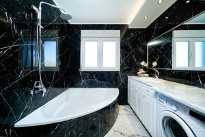 a black bathroom with a tub and a washing machine at Villa Valia Calda in Limenas +61 photos