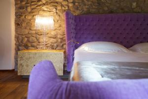 - une chambre avec un lit violet et une table avec une lampe dans l'établissement Il Portico - 1711 Luxury Guest House, à Arlate