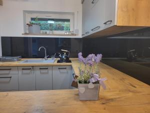 a kitchen with a vase with purple flowers on a table at Zacisze Huta in Huta