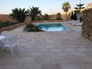 a swimming pool in a patio with chairs and a table at Newly Converted One of a Kind Farmhouse Villa In Gozo in Għarb
