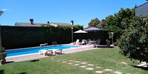 einen Pool mit Stühlen, einem Tisch und einem Sonnenschirm in der Unterkunft patricia in Villaviciosa de Odón