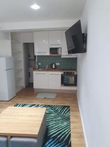 a kitchen with white cabinets and a tv on the wall at Superbe logement proche de CDG- Parc d'expo- Paris in Aulnay-sous-Bois