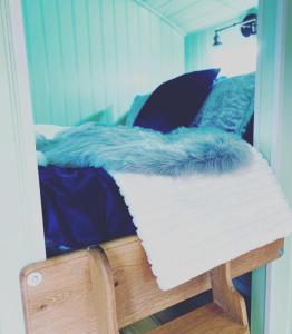 a bed with a blue and white comforter on it at Jasmine The Shepherd Hut in Woodhall Spa