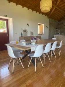 uma sala de jantar com uma mesa de madeira e cadeiras brancas em Casa do Afonso em Brufe