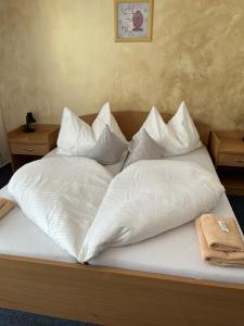 uma cama com lençóis brancos e almofadas em Raketa Residence, hotel & restaurant em Brezany