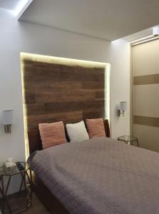 um quarto com uma cama grande e uma cabeceira em madeira em Dévai-LUX Apartman Sárvár em Sárvár