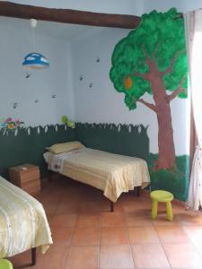 Habitación con 2 camas y un árbol pintado en la pared. en Casa Mandarino Forio Ischia en Ischia