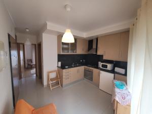 a small kitchen with a stove and a microwave at Alojamento Valverde in Nazaré