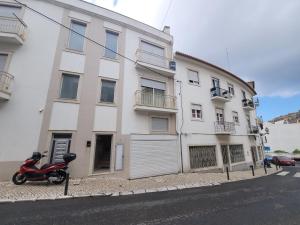 a scooter parked in front of a white building at Alojamento Valverde in Nazaré