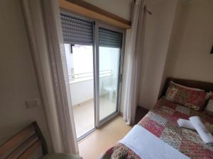 1 dormitorio con 1 cama y puerta corredera de cristal en Alojamento Valverde, en Nazaré