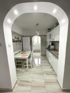 a kitchen with a table and a white kitchen with an archway at Residence RMZ in Mangalia