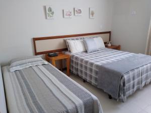 a bedroom with two beds and a night stand at Flat Bairro Nobre - Bertioga in Bertioga