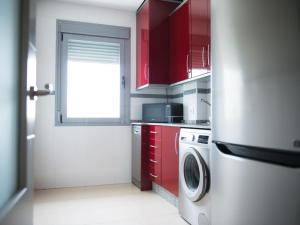 a kitchen with red cabinets and a washing machine at Apartamento Puerta del Sol in Conil de la Frontera
