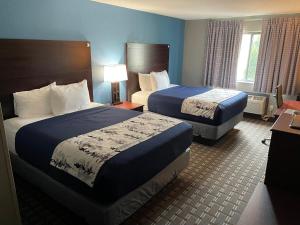 a hotel room with two beds and a lamp at American Inn Cedar Rapids South in Cedar Rapids