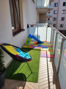 uma varanda com uma cadeira e um parque infantil em Apartament Rainbow em Bialystok