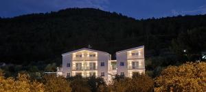 a building on a hill with a mountain in the background at Harmony Thassos suites & Apartments in Skala Rachoniou