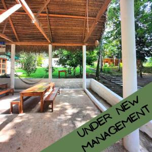 un pabellón al aire libre con mesa de madera y bancos en Pachamaya River Hostel en Lanquín