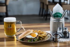 a plate with a sandwich and fries and a mug of beer at Farmhotel Efstidalur in Laugarvatn