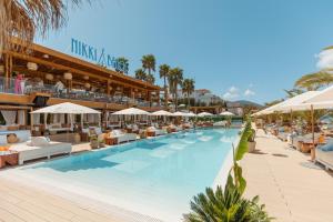 a swimming pool with chairs and umbrellas at a resort at Nikki Beach Resort & Spa Montenegro in Tivat