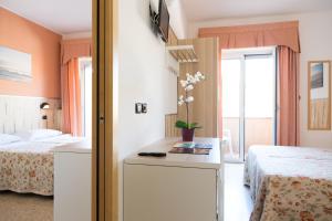 a bedroom with two beds and a table with flowers on it at Hotel Saint Tropez - Pineto in Pineto