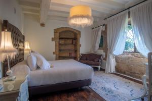 a bedroom with a bed and a chair and a chandelier at Hotel Casa del Marqués in Santillana del Mar