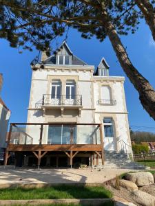 Un grand bâtiment blanc avec balcon est disponible. dans l'établissement La Source - Villa wissantaise, à Wissant