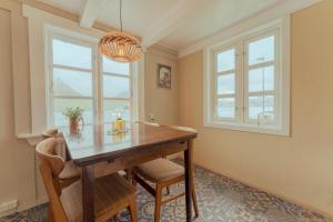 a dining room with a table and two windows at Authentic Faroese House / Unique Location / Nature in Hellur