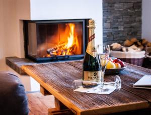 a bottle of champagne on a wooden table in front of a fireplace at Tauernwelt - Chalet Hochkönigblick in Maria Alm am Steinernen Meer