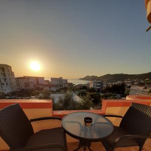 a table and chairs on a balcony with the sunset at Apartments Nurkovic in Dobra Voda