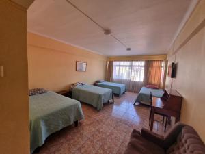 a hotel room with two beds and a desk at HOTEL ASTORE Matta 2537 in Antofagasta