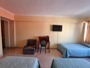 a room with two beds and a desk and a television at HOTEL ASTORE Matta 2537 in Antofagasta