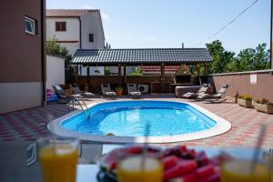 a swimming pool with chairs and orange juice on a patio at Lucija in Starigrad