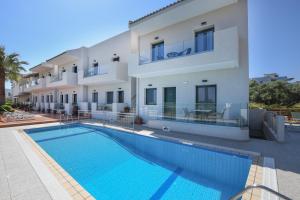 a villa with a swimming pool in front of a building at Aspri Petra Apartments in Hersonissos