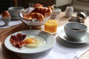 a breakfast table with a plate of eggs bacon and orange juice at Hôtel Le Gentleman in La Flèche