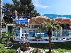 a restaurant with blue chairs and an umbrella and palm trees at Beach Falésia in Albufeira