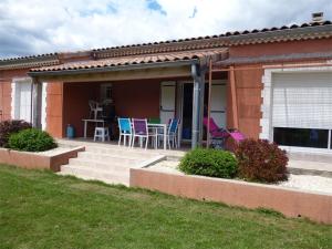 a house with a patio with chairs and a table at villa Soleil 3chambres piscine in Lagorce