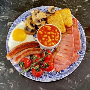 a plate of breakfast food with eggs bacon tomatoes and mushrooms at Eagle House - Award Winning B&B and Apartment in Eccleshall