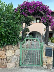 una puerta verde frente a un edificio con flores púrpuras en Casa Souad, a cheerful and charming beach view 2 bedroom house and free parking, en Porto San Paolo
