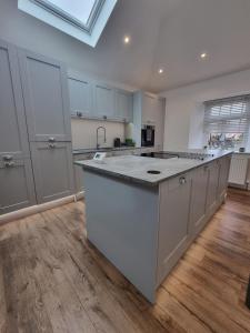 a large kitchen with white cabinets and a large island at Beautiful 2 bedroom home with private bar below in Ystradgynlais