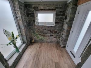 a room with a brick wall and a window at Beautiful 2 bedroom home with private bar below in Ystradgynlais