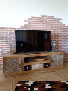 telewizor z płaskim ekranem siedzący na szczycie drewnianego centrum rozrywki w obiekcie Casa del Norte w mieście Brackenheim