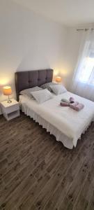 a bedroom with a large bed with white sheets and wood floors at Lavanda in Vrana