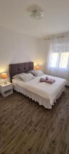 a bedroom with a large bed with white sheets and wood floors at Lavanda in Vrana