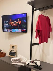 a tv on a wall with a red shirt on a shelf at Pineta158 in Cagliari