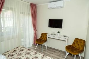 a room with a desk and two chairs and a tv at Pensiunea Casablanca in Reghin